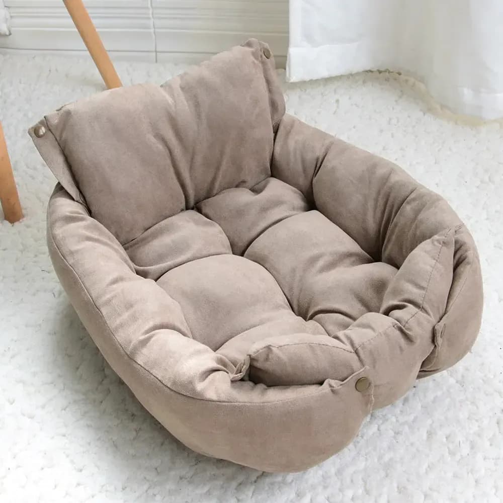 Beige cushioned pet bed with a soft tufted centre and raised padded sides displayed on a wooden floor.