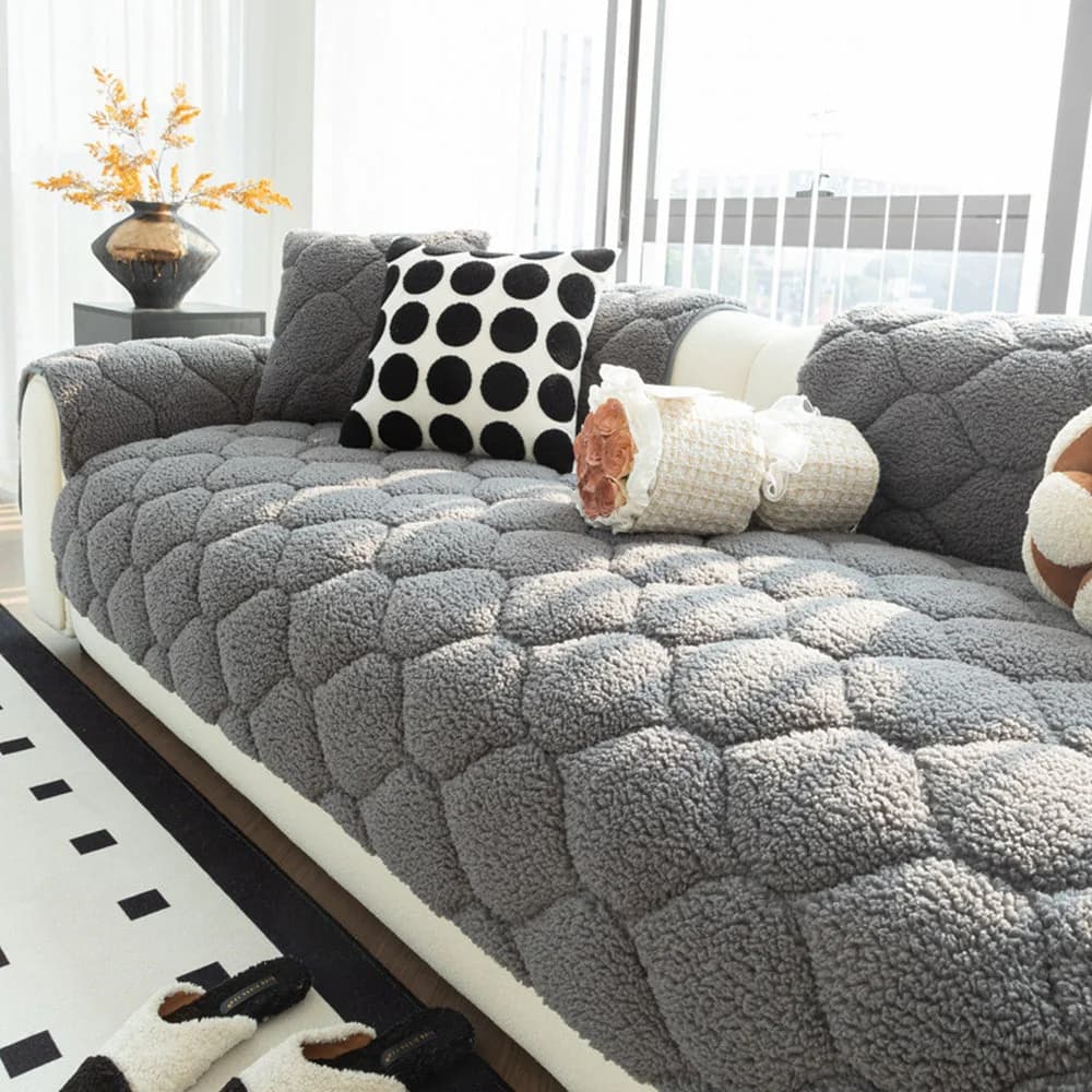 Dark grey quilted sherpa fleece sofa cover neatly fitted over a couch with soft cushions and pet friendly protection