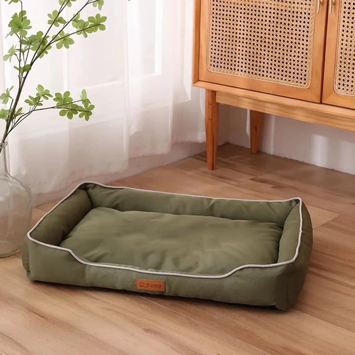 Green rectangular cushioned dog bed with raised supportive sides displayed in a bright modern home.
