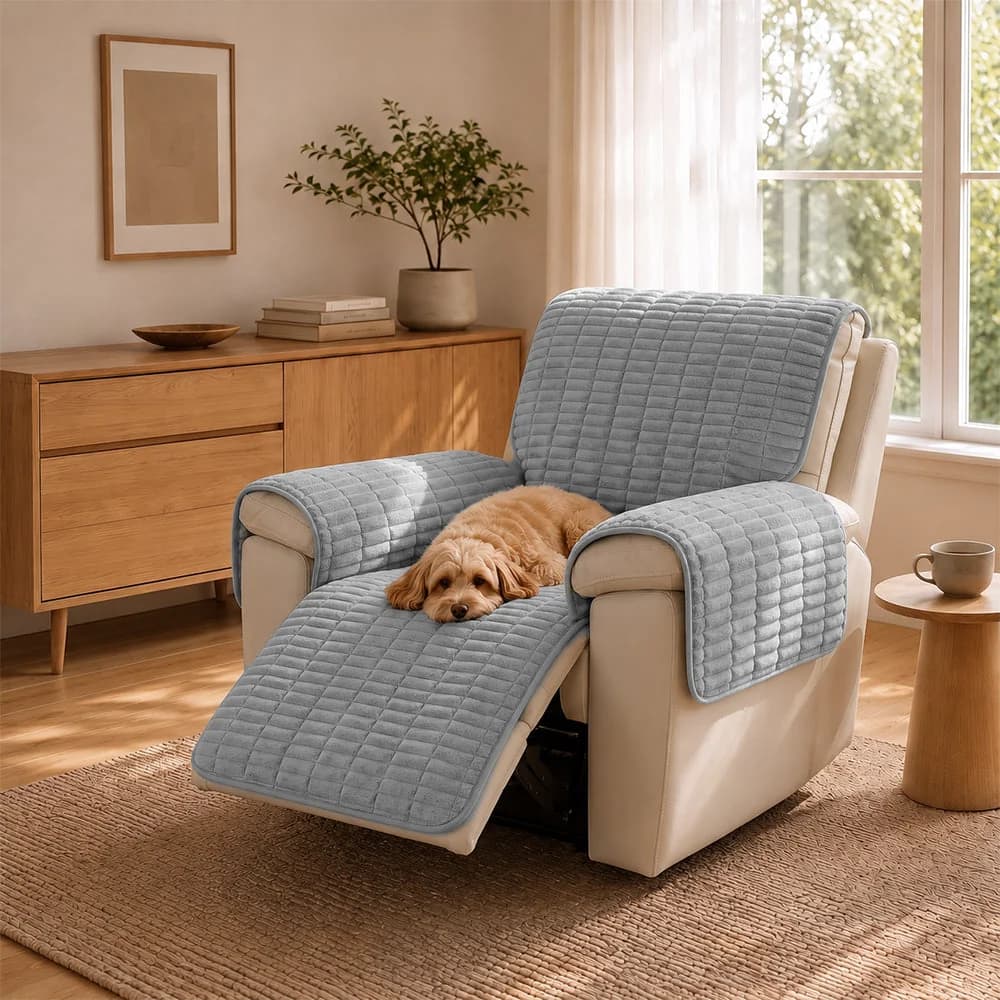 Cat resting on a grey quilted recliner chair protector with coverage across the seat and footrest.