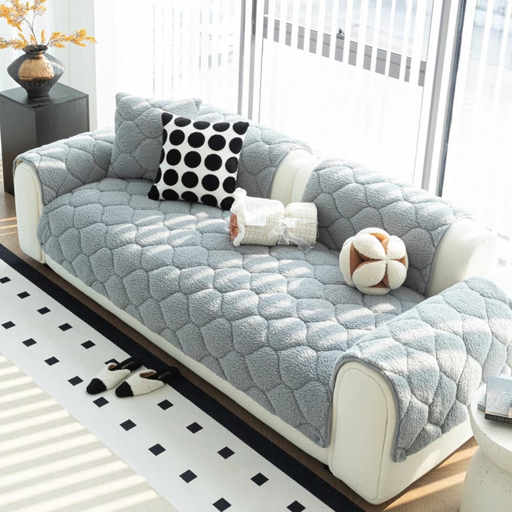 Small dog relaxing on a grey quilted sherpa fleece sofa cover protecting a modern living room couch