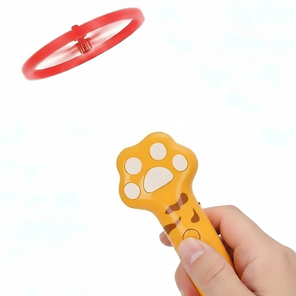 Yellow paw shaped handheld cat toy launcher with a red flying disc shown against a white background